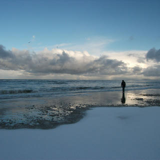Silohuette of a figure on the snowy beach.